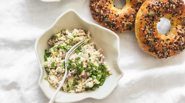 Bagels alongside bowl of chopped and combined ingredients