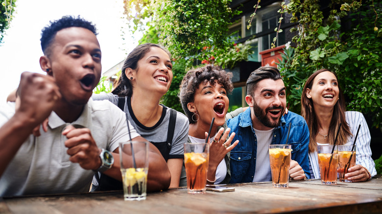 group of friends drinking and cheering at sports bar