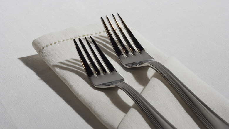 Forks and a white napkin are laid out in a table setting.