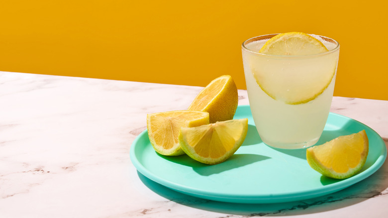 lemon wedges on plate with glass of lemonade