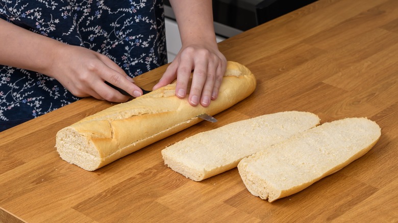 Person cutting French bread loaf