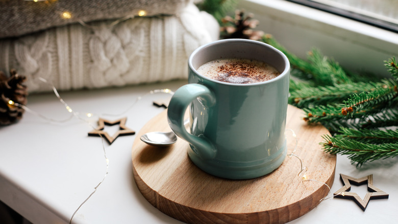 A mug of hot cocoa with holiday lights and decorations.