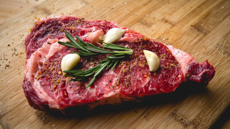 Raw ribeye steak with garlic and rosemary