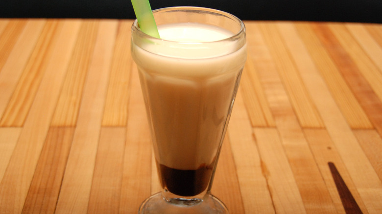 an egg cream in a soda glass on a counter