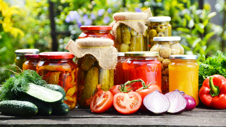 Glass jars of pickled vegetables in a garden