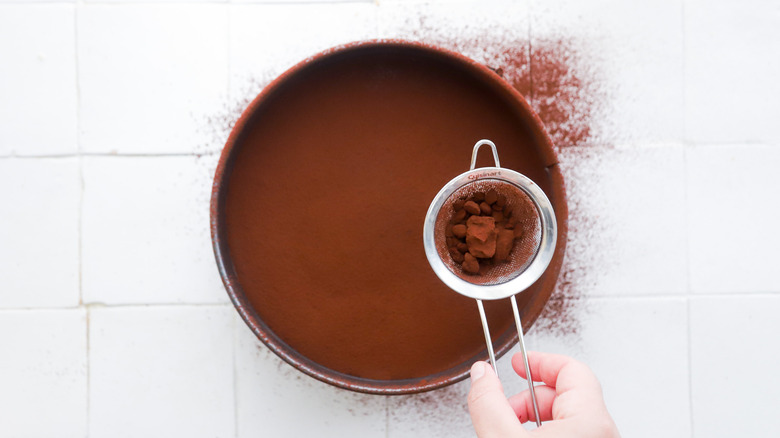 Dusting cocoa powder over cheesecake