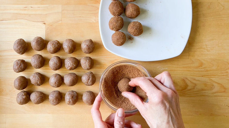 Rolling no-bake snickerdoodle cookie dough balls in cinnamon sugar