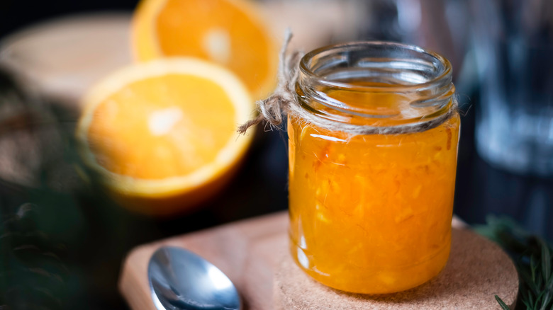 Jar of homemade marmalade and sliced oranges