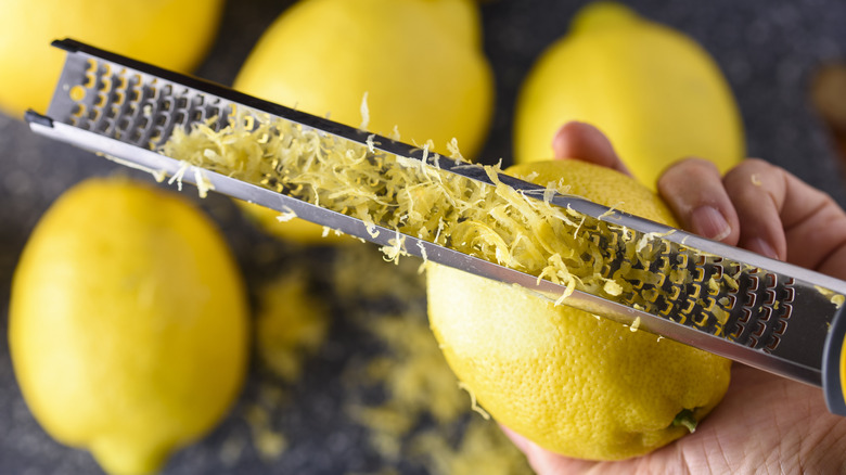 Closeup of person grating lemon zest on microplane
