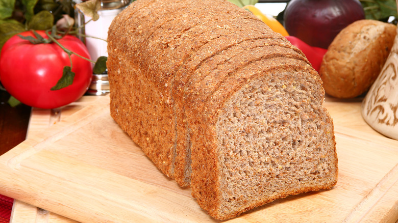 Loaf of sprouted whole grain slice bread on wood cutting board