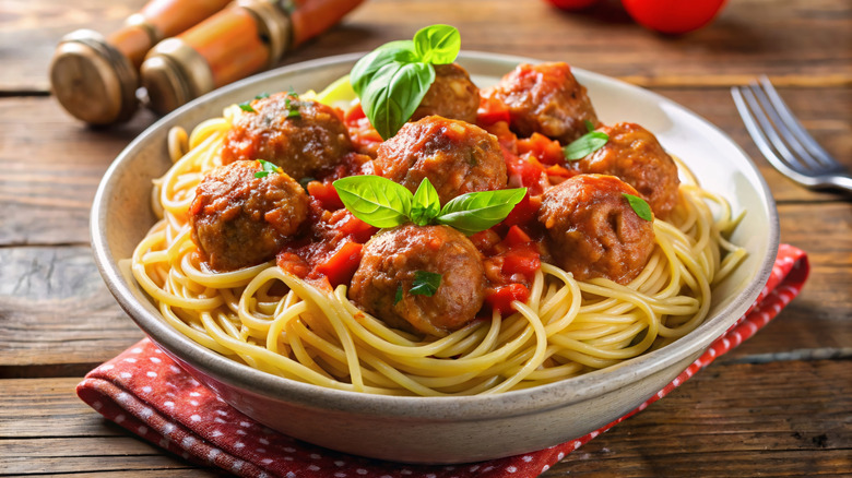 A bowl of spaghetti and meatballs with a basil garnish