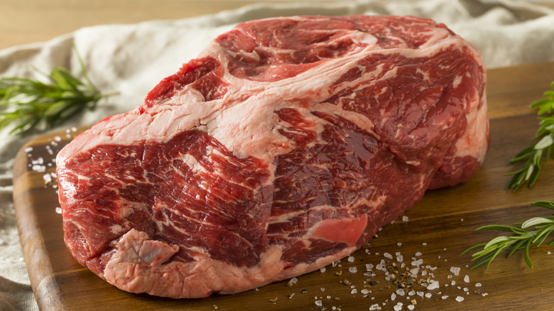 Raw chuck steak on wooden board.