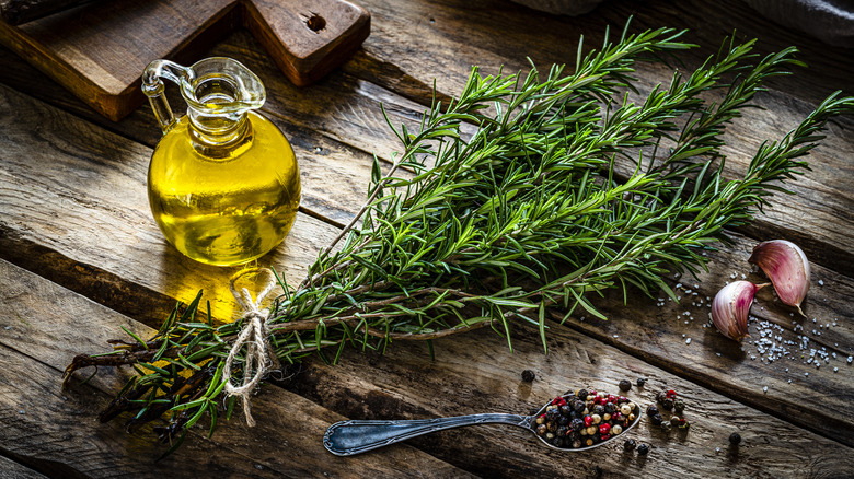 Bunch of fresh rosemary and bottle of oil on a wooden table