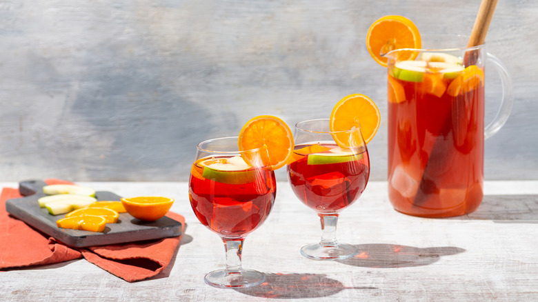 pitcher cocktail with two coupe glasses, orange slices, and apple slices