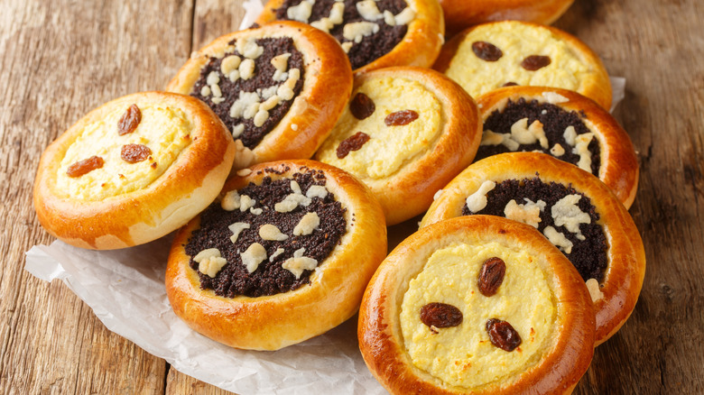 Round baked pastries with yellow and brown filling are arranged on a wooden background.