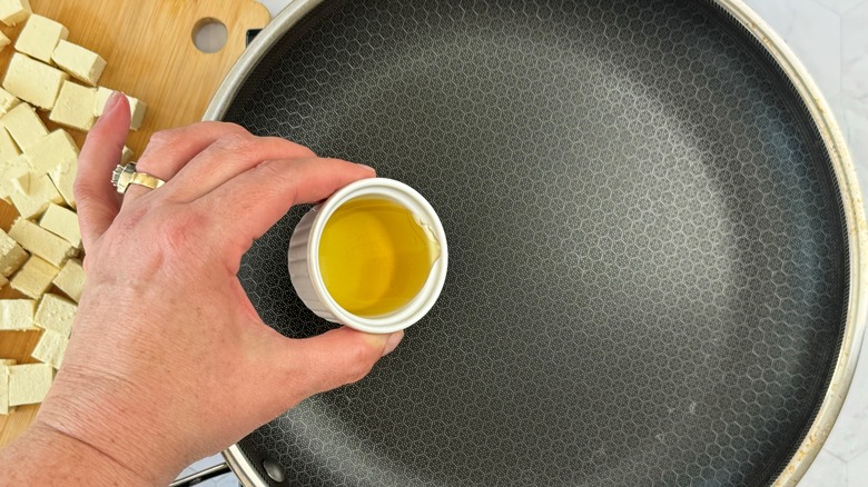 hand holding oil over pan