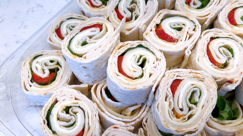 A display of pinwheel sandwiches sits in a glass dish.