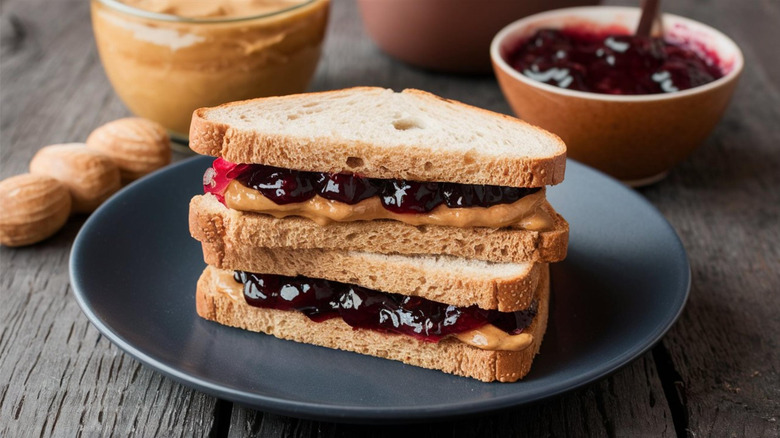 A peanut butter and jelly sandwich made with whole wheat bread sits on a plate