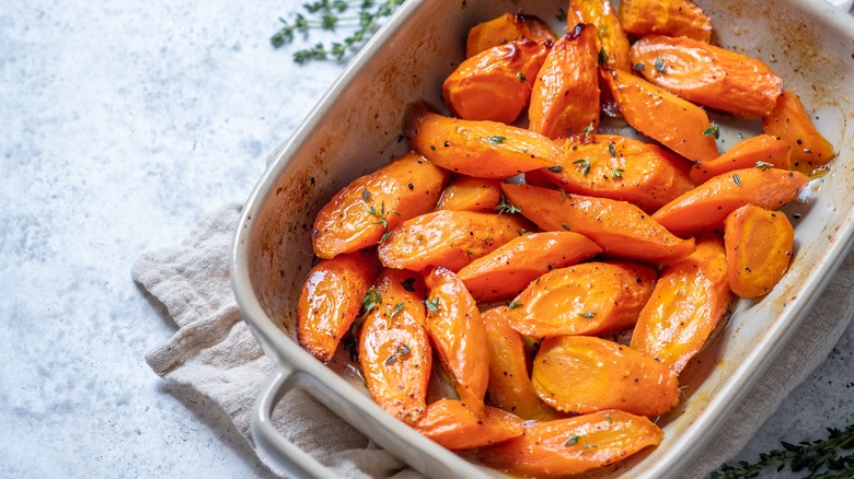 A dish of glazed, candied carrots sprinkled with dry herbs.