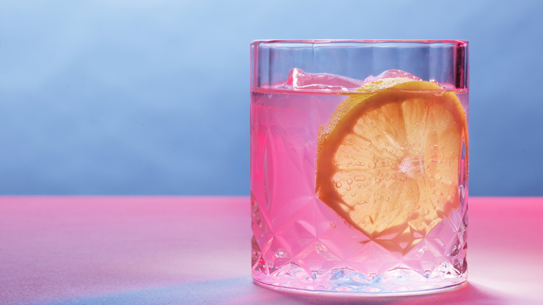 A pink cocktail or mocktail has a lemon slice