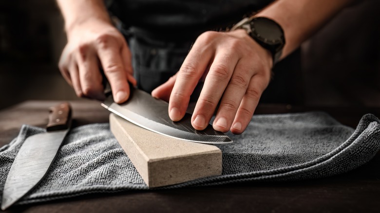 Hands sharpening knife on stone