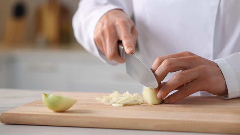 Chef chopping onions on board