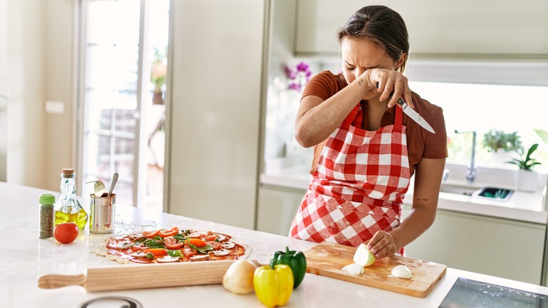 Woman crying while cutting onions
