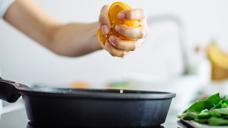 squeezing orange into frying pan