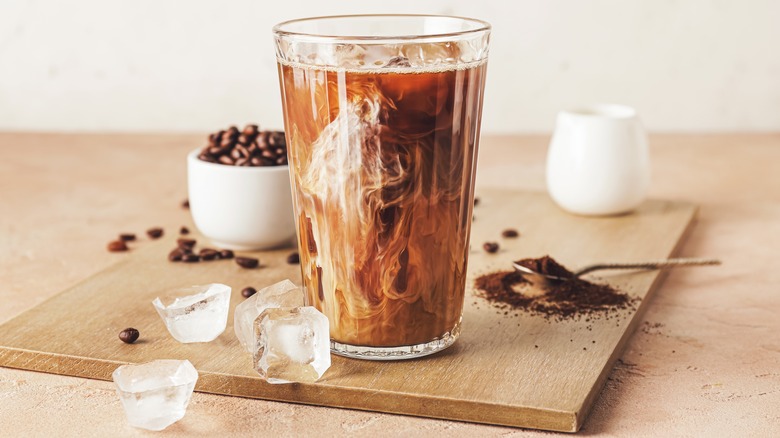 Iced coffee in glass with swirling cream, ice, coffee beans