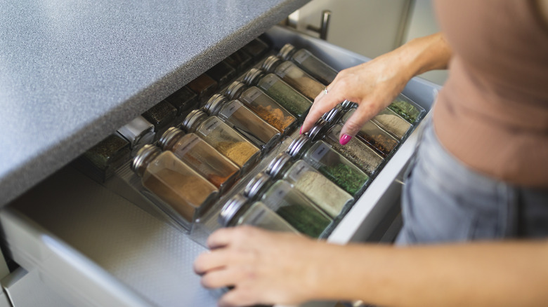 Someone opening their kitchen drawer, revealing a selection of organized spices.