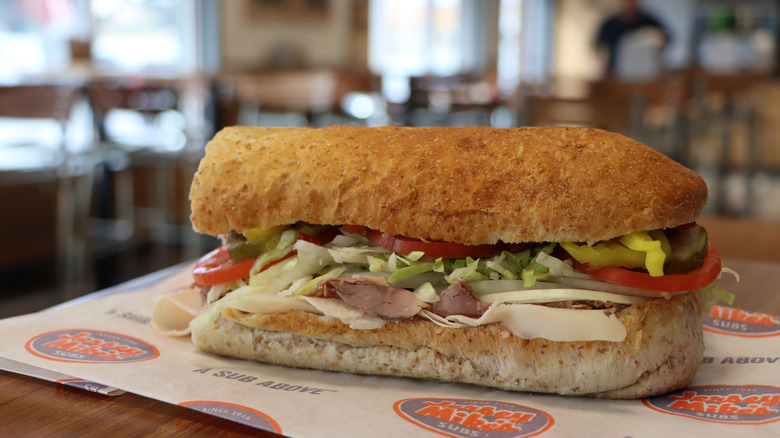 Sub sandwich with meat, cheese, and veggies on Jersey Mike's paper on a restaurant table