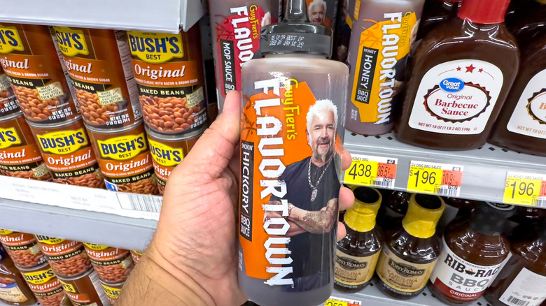 Someone holds Guy Fieri's Hickory barbecue Flavortown sauce at a grocery store