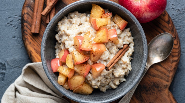 A bowl of oatmeal with apples and cinnamon sticks