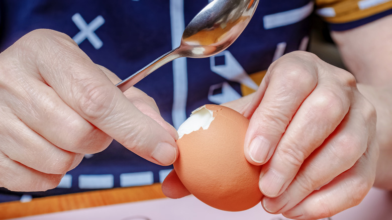 Person using spoon on hard-boiled egg