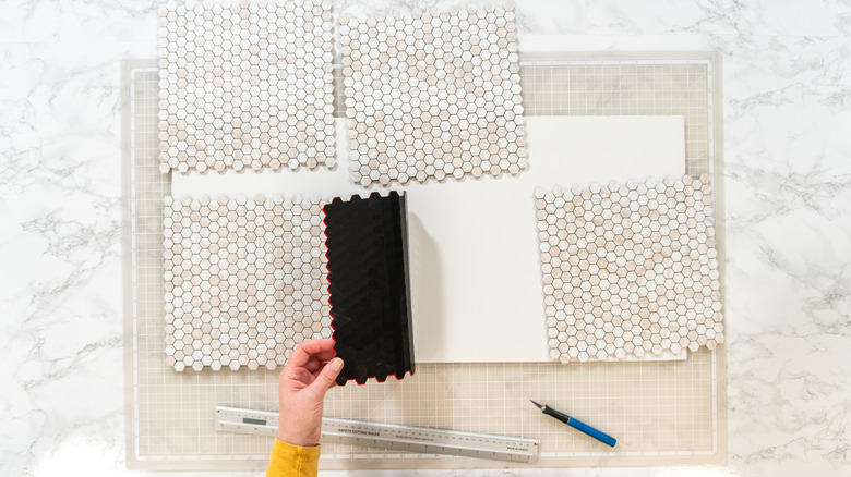 Hands removing peel-and-stick tile from a foam board