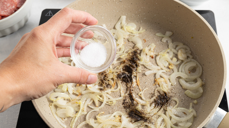 adding salt and pepper to cooked onion in pan