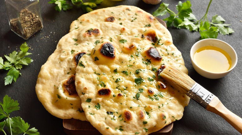 Naan brushed with ghee and herbs on black surface