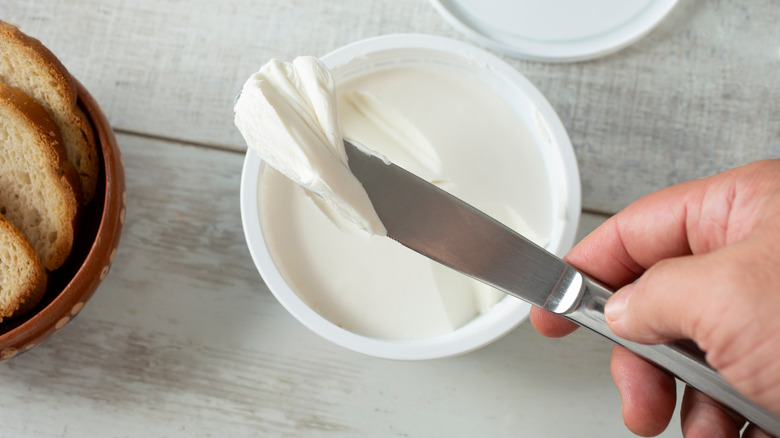 Cream cheese being scooped onto a butter knife