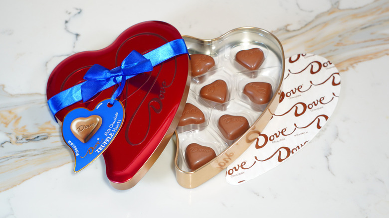 An open heart-shaped tin of Dove chocolates