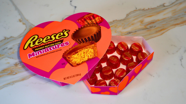 An open heart-shaped box of Reese's Peanut Butter Cup Miniatures with the lid leaning to the left