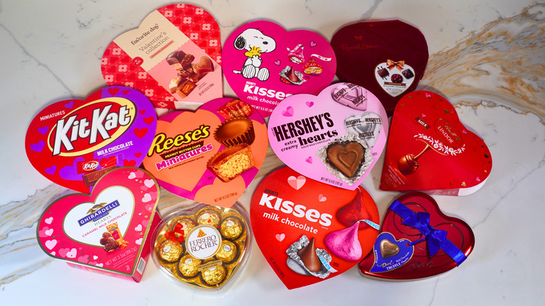 Eleven closed heart-shaped boxes of chocolate arranged on a marble counter