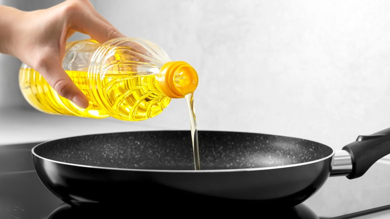 a person pouring oil into a pan