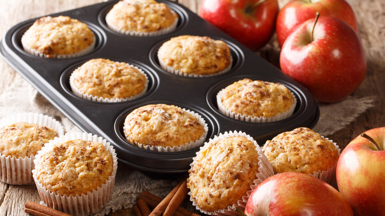 muffins in a tin and on a table with apples