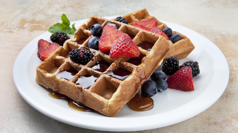 Waffles topped with berries and syrup on plate