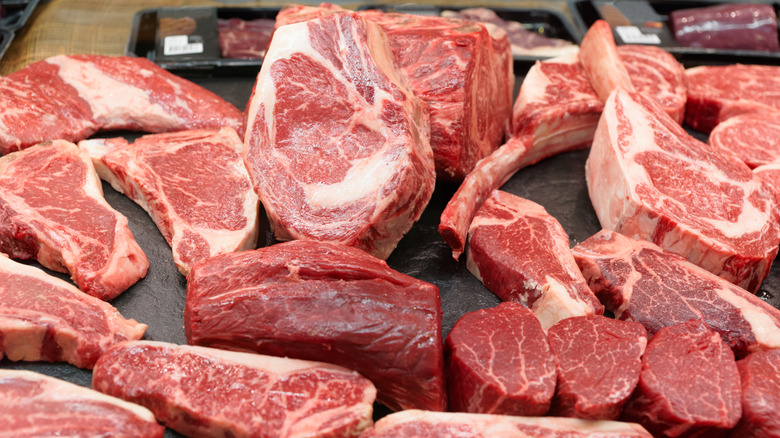 Cuts of raw beef gathered on a butcher's display shelf