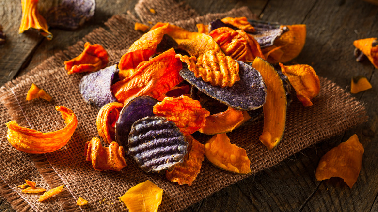 A selection of vegetable chips rest on a burlap sack