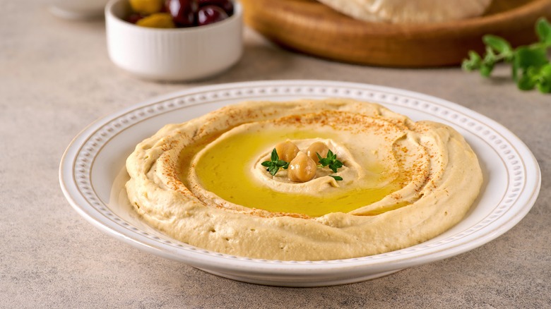 Plate of hummus topped with chickpeas, oil, and herbs