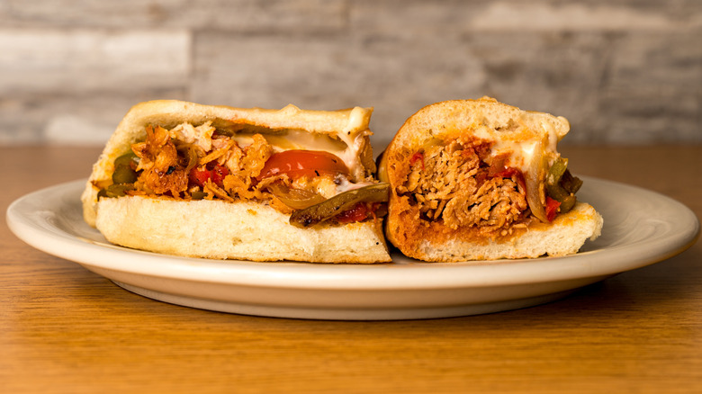 Cheesesteak sandwich on a plate filled with turkey or chicken, peppers, and cheese