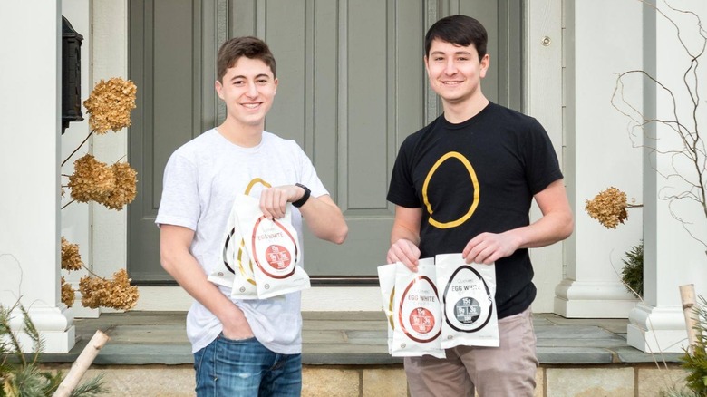 Nick Hamburger and Zack Schreier of Quevos posing while holding bags of Quevos chips