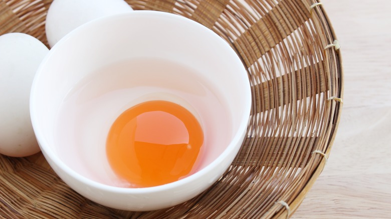 egg cracked into white ramekin